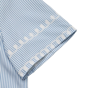 Detailed close-up of blue and white striped shirt cuff with elegant white wave embroidery