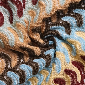 Detailed close-up of multi-color ethnic style crochet knit fabric with wavy lace patterns