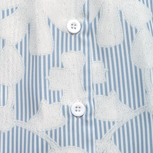 Macro shot of vertical blue stripes fabric with white floral prints and resin buttons