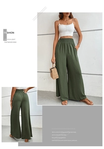 Detail of high-waist wide-leg trousers in dark green with elastic pleated waistband texture