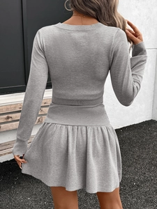 Detailed close-up of grey knitted crop top and pleated mini skirt showing ribbed texture