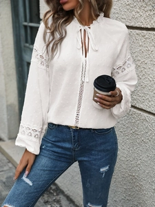 Detailed view of white lace hollow shirt with polka dot texture and tie-neck detail