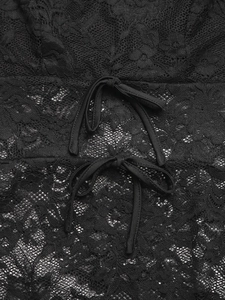 Détail macro du tissu en dentelle florale noire avec deux petits rubans et nœuds décoratifs