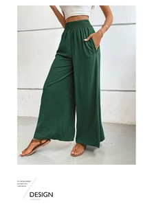Detail of high waist elastic waistband and textured fabric on dark green wide leg pants