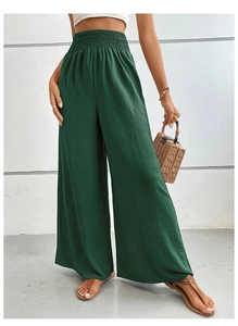 Detail of high-waisted smocked waistband on dark green wide-leg trousers for women
