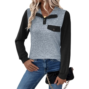 Detail eines Colorblock-Hoodies mit Kontrastknöpfen und Vordertasche auf grauem Strick