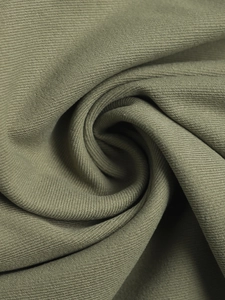 Detail von armeegrünem Köperstoff mit spiralförmiger Faltenstruktur und Materialdichte