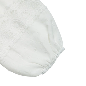 Detailed close-up of white Swiss dot fabric sleeve with lace trim and elastic cuff