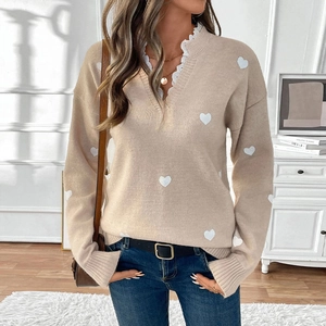 Close-up of white heart knit pattern and delicate lace trim on apricot V-neck sweater