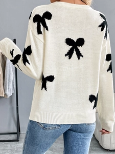 Detail of white knit sweater showing black bow jacquard pattern and ribbed hem on back