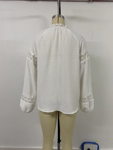 Detail of white long sleeve blouse featuring dobby dot texture and lace hollow out sleeves