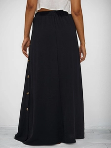 Detail of black maxi skirt with elastic waistband and decorative wood buttons