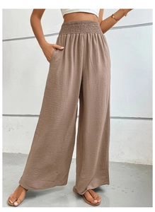 Detail of high waisted smocked waistline on tan wide leg trousers with soft texture