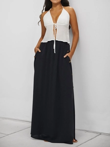 Detail of black high-waisted maxi skirt featuring side decorative buttons and pockets