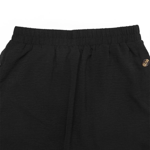 Detail of elastic waist and amber-textured button on black casual skirt fabric