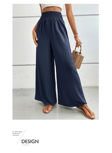 Detail of smocked high waist and vertical texture on navy blue wide-leg trousers