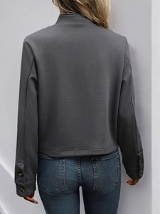 Detail of dark grey textured jacket with stand collar and decorative cuff buttons