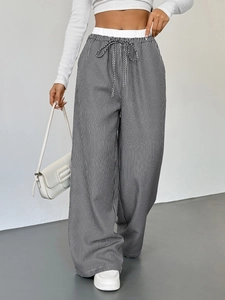 Dettaglio dei pantaloni a gamba larga a vita alta con strisce verticali bianche e nere e coulisse