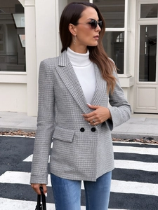 Close-up of houndstooth blazer featuring double-breasted buttons and flap pockets