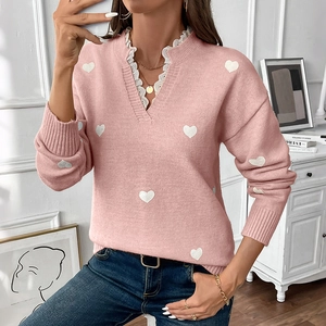 Detail of pink knit sweater showing V-neckline with delicate white lace and heart pattern
