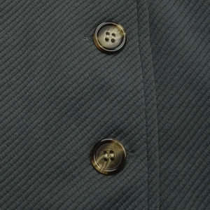 Close-up of textured twill fabric and vintage tortoiseshell buttons on gray jacket