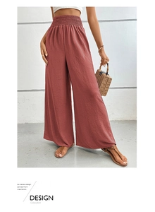 Detail of high-waisted smocked waistband on rust red textured wide-leg summer trousers
