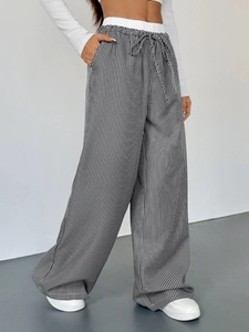 Dettaglio dei pantaloni a righe a vita alta con fascia elastica e coulisse regolabile