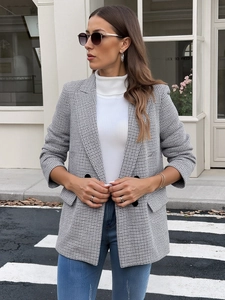 Detail of women's houndstooth blazer featuring notched lapels and flap pockets