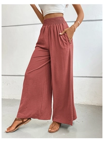 Detailed macro shot of the high waist smocked elastic waistband on women's red wide leg pants