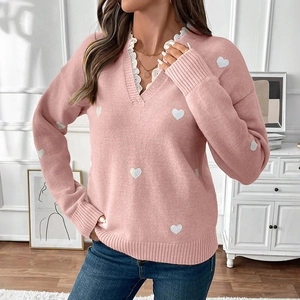 Detail of V-neckline with white lace trim and heart pattern on pink knitted sweater