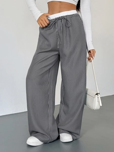 Dettaglio dei pantaloni larghi a righe verticali bianche e nere con coulisse in vita