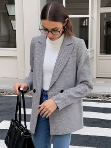 Detailed street style shot of women's gray houndstooth blazer with double-breasted buttons