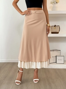 Detail view of pink high-waist tiered skirt with gold buttons and white pleated hem