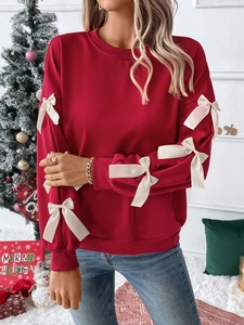 Detail of red crewneck sweatshirt featuring decorative white satin bows on the sleeves
