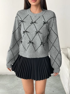 Detail of argyle knit sweater with 3D black bows and pearl beads on grey fabric