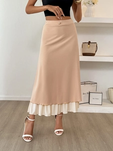 Detail of high waist skirt featuring pearl button and white ruffled layer hemline