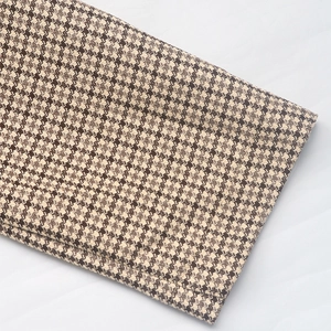 Detailed close-up of brown houndstooth pattern fabric on an elegant plaid blazer