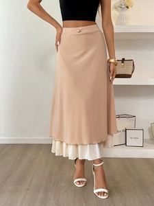 Detail of A-line skirt with decorative pearl button and layered pleated hem design