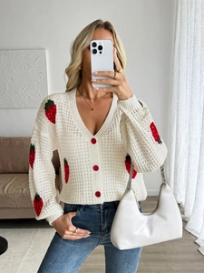 Detailed view of white V-neck cardigan featuring red strawberry knits and red buttons