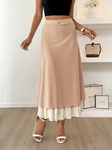Detail of apricot midi skirt showing layered hem with cream pleated lace and pearl button