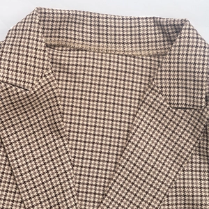 Close-up of notched lapel on a brown houndstooth blazer with fine woven texture