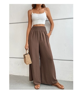 Detail view of brown wide leg trousers showing vertical ribbed texture and elastic high waist