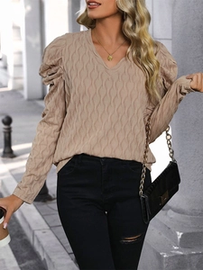 Detail shot of the V-neck texture and puff sleeves on a beige long-sleeved casual top