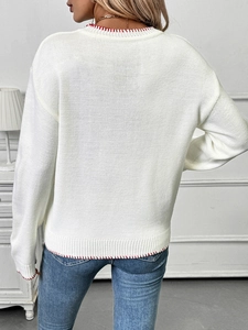 Detail view of white knit sweater featuring red contrast stitching and textured fabric