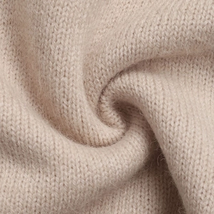 Close-up of soft beige knit sweater fabric with premium wool texture and ribbed pattern