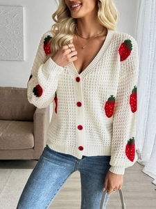Close-up of white crochet cardigan featuring red strawberry jacquard and red buttons