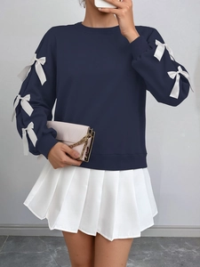 Detail of navy blue sweatshirt featuring white decorative bows on the sleeves and round neck