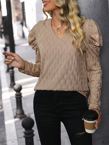 Detail of V-neck knitted top featuring puff sleeves and textured wavy fabric pattern