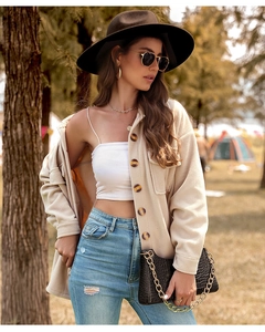 Détail d'un cardigan en polaire beige à boutons foncés et d'un sac noir en cuir croco