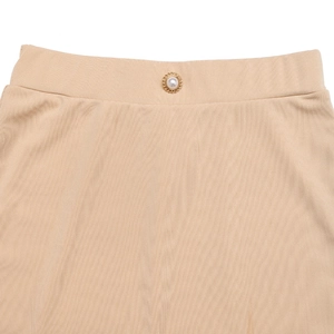 Detail view of beige A-line skirt waist featuring textured fabric and a gold pearl button